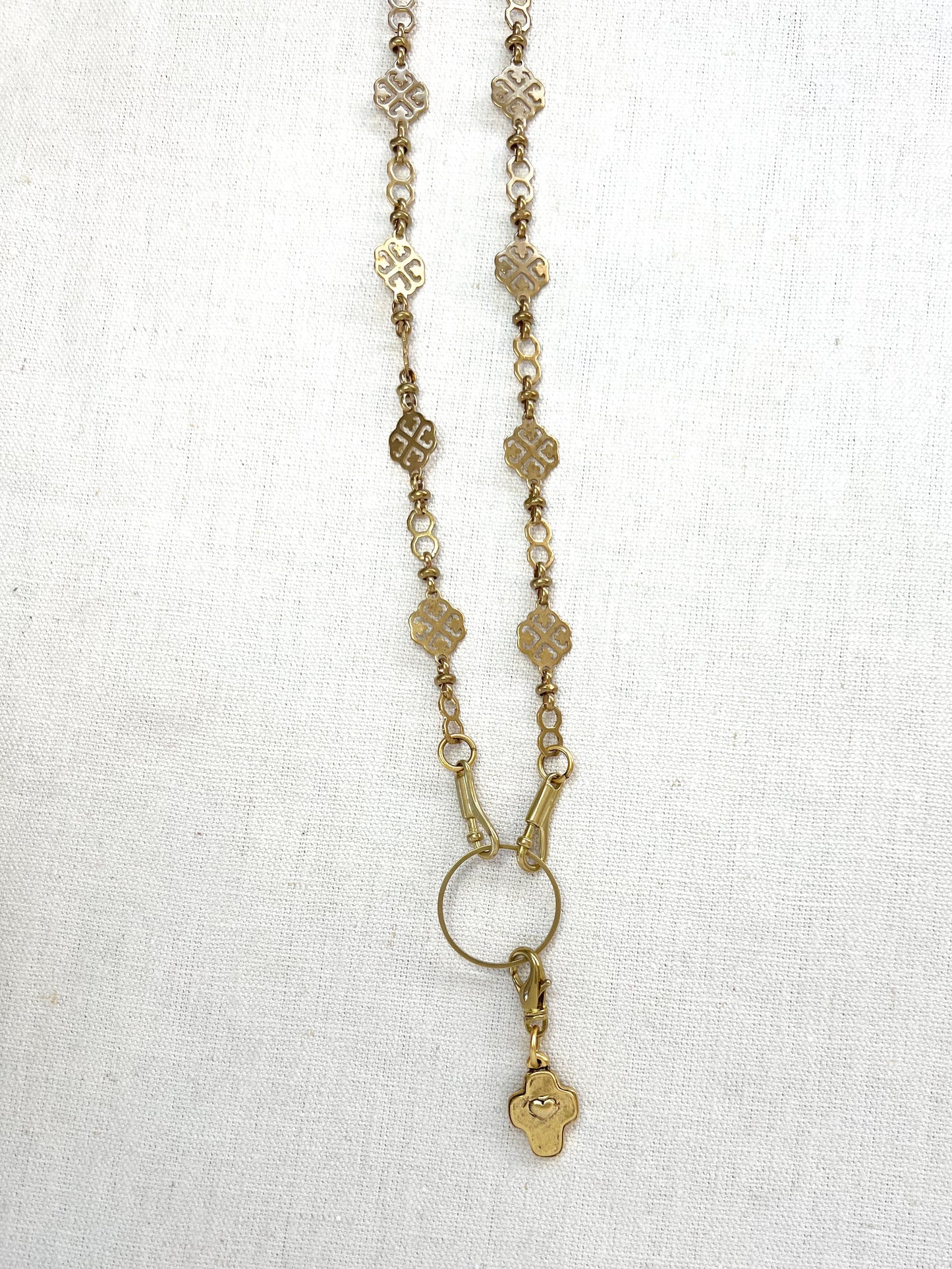 Gold necklace with a cross charm pendant on a white background