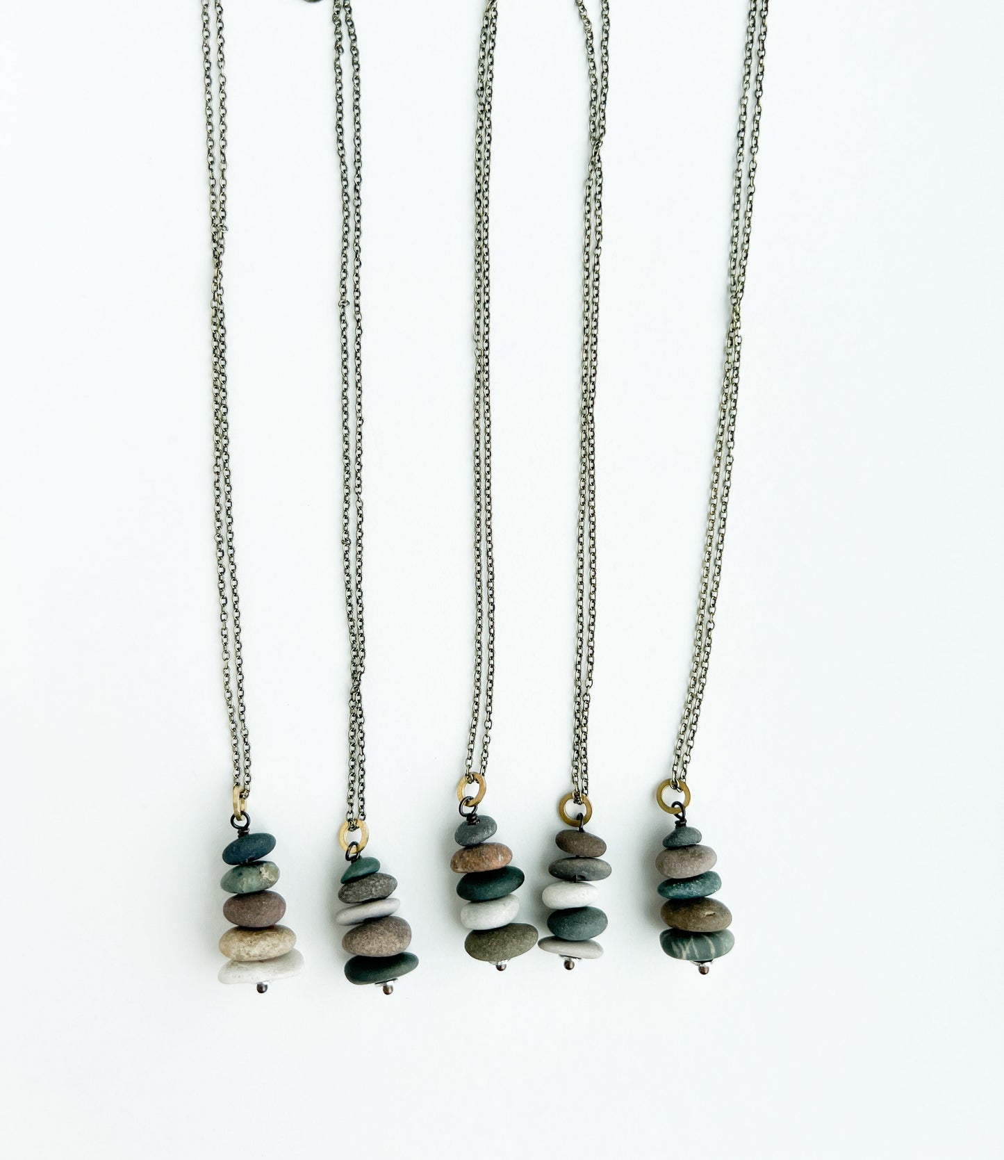 Five necklaces with stone pendants on a white background