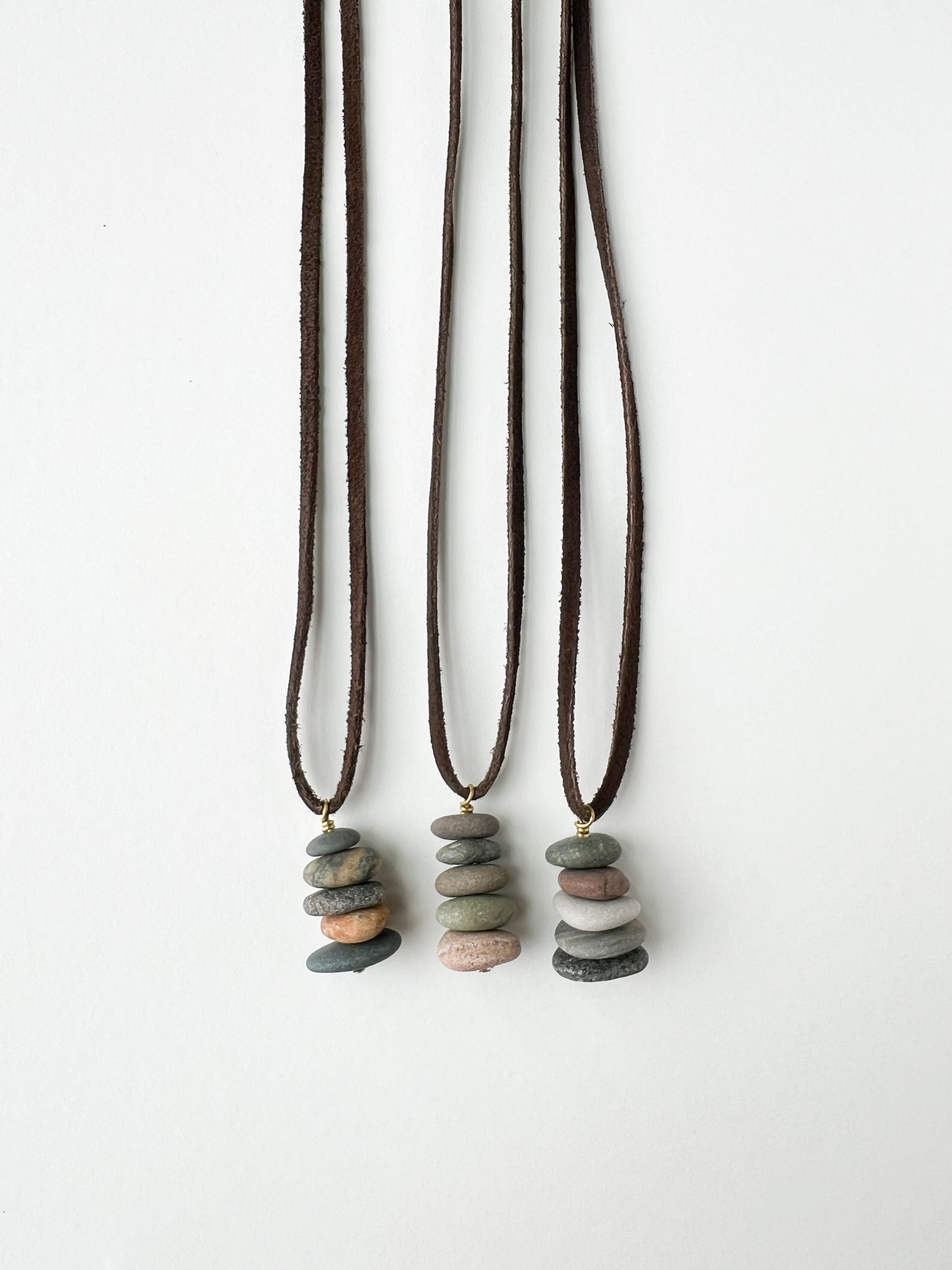 Three necklaces with stone pendants on a white background