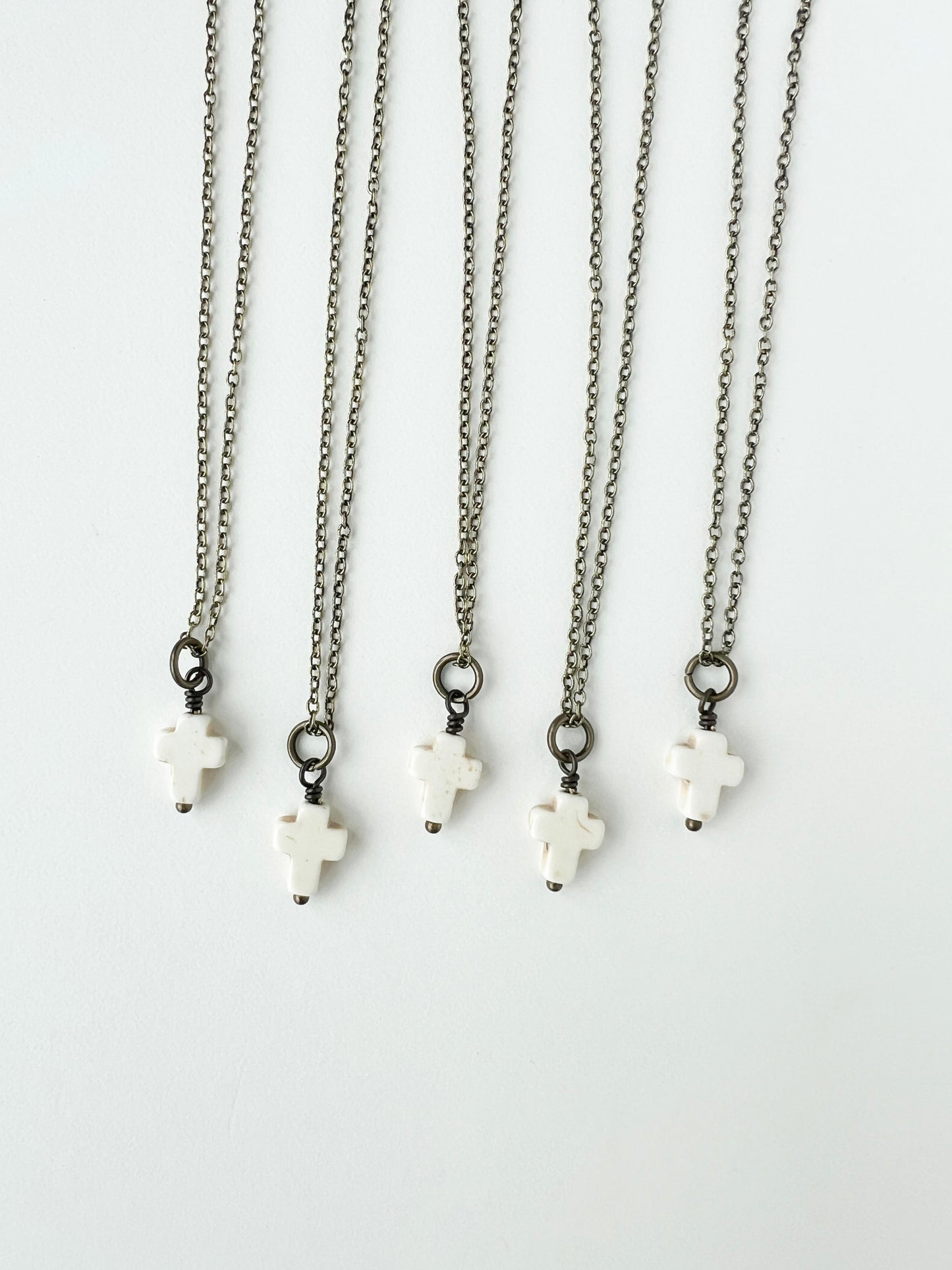 Set of five necklaces with white cross pendants on a white background