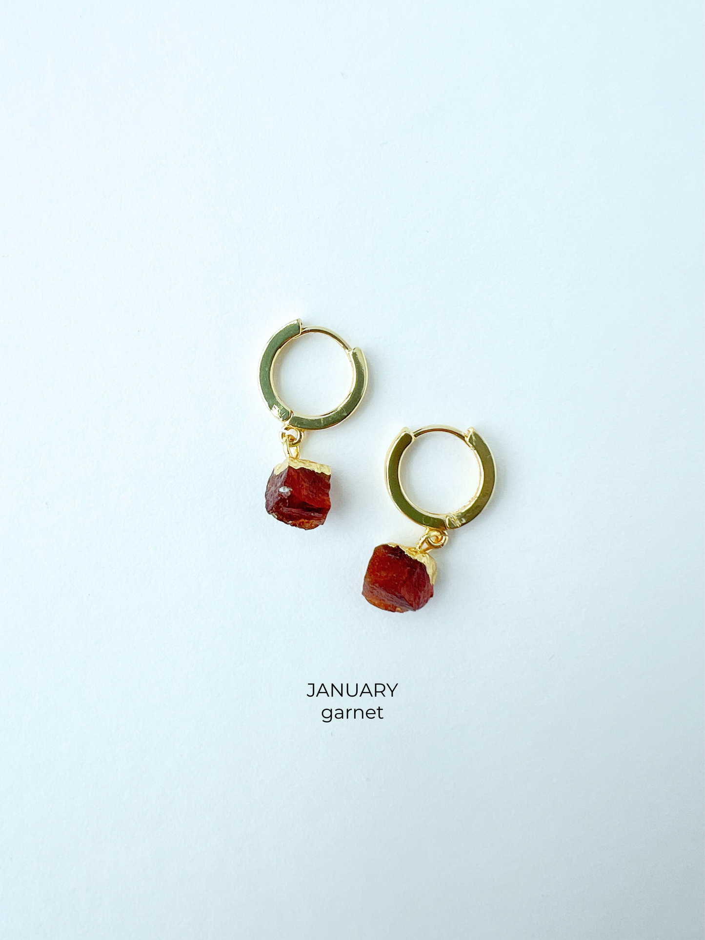 Gold huggie style birthstone earrings in January garnet