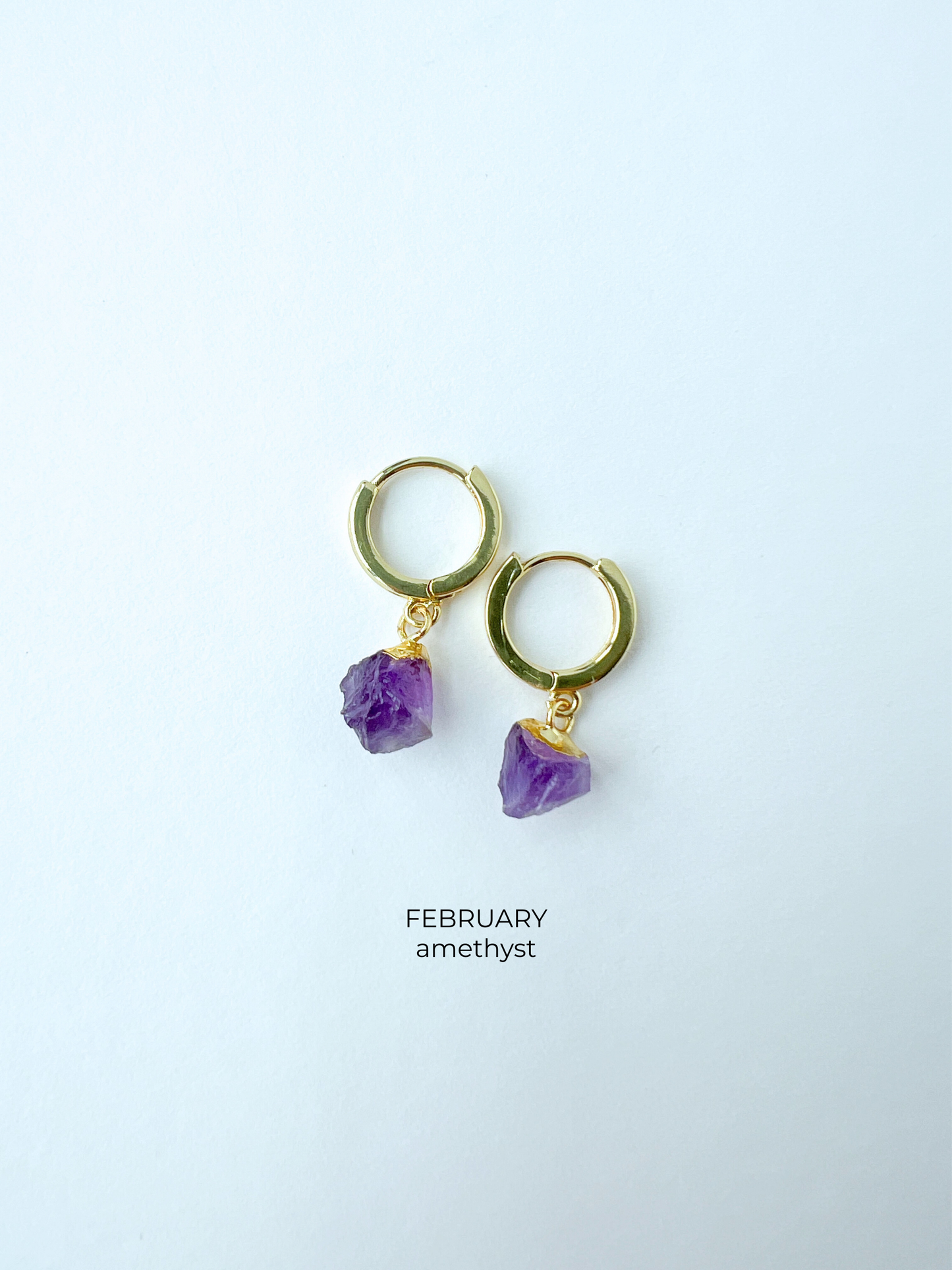 Gold huggie style birthstone earrings in February amethyst