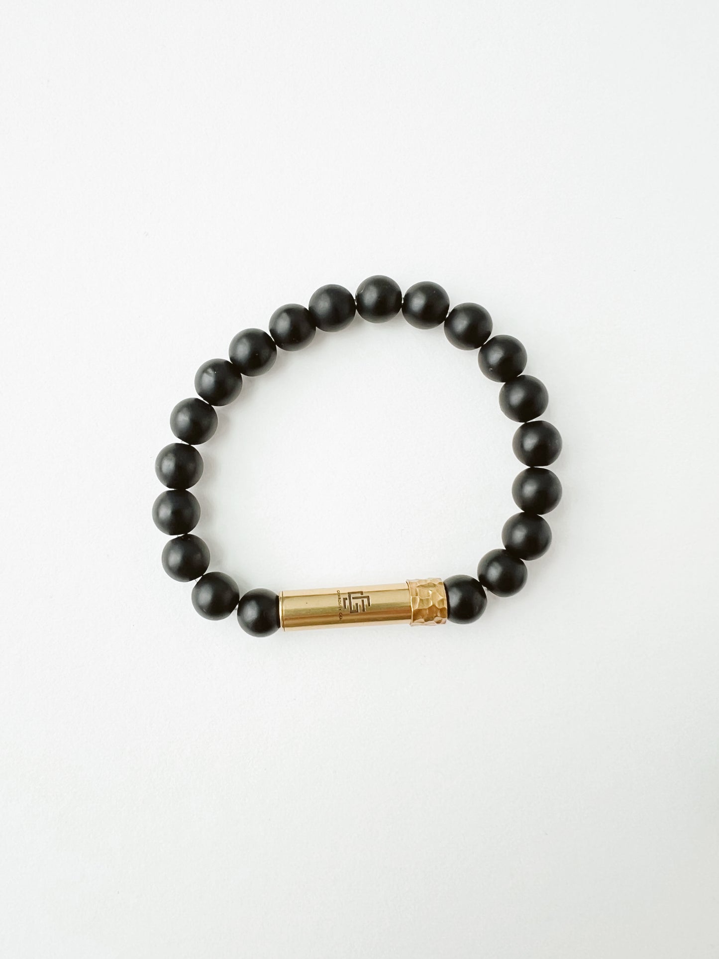 Black beaded bracelet with a gold tube clasp on a white background