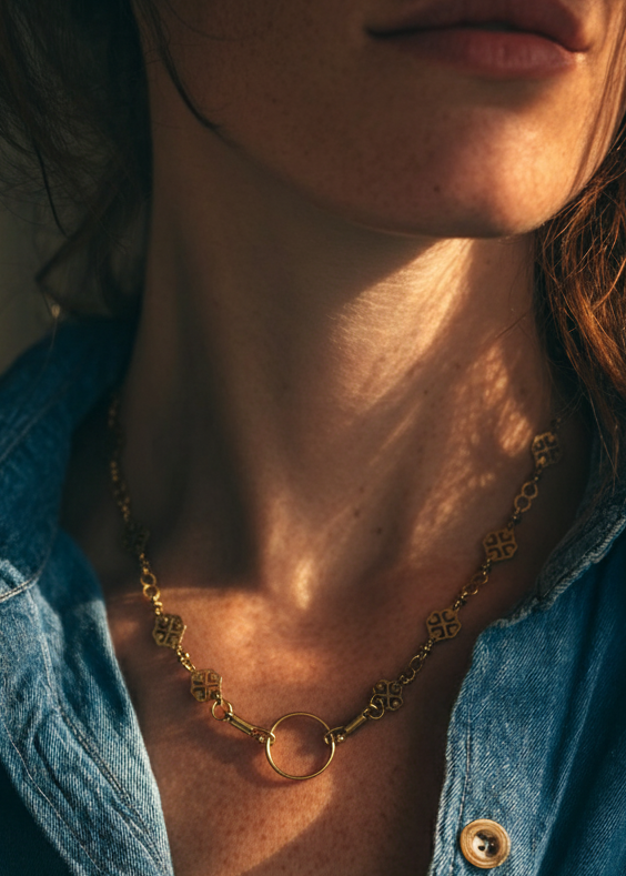 Close-up of a person wearing a blue denim shirt and gold necklace with a blurred background