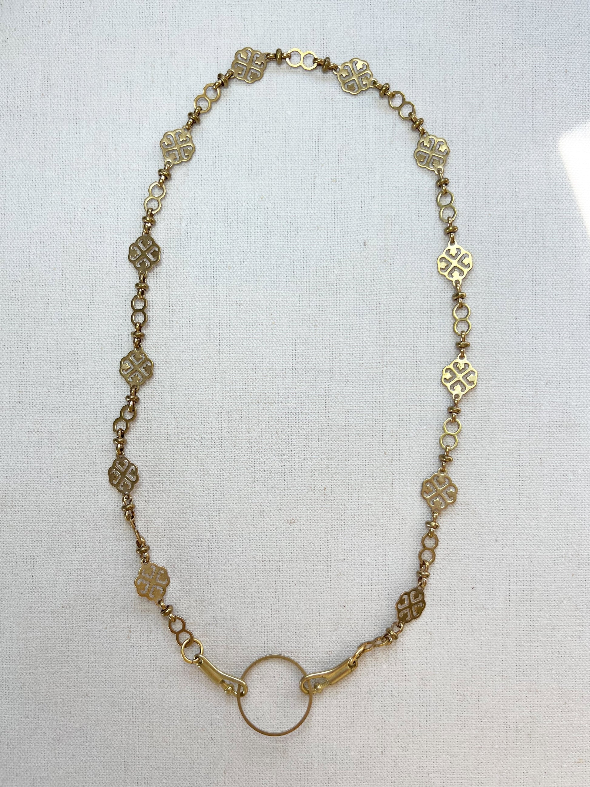 Gold necklace with floral links on a white background