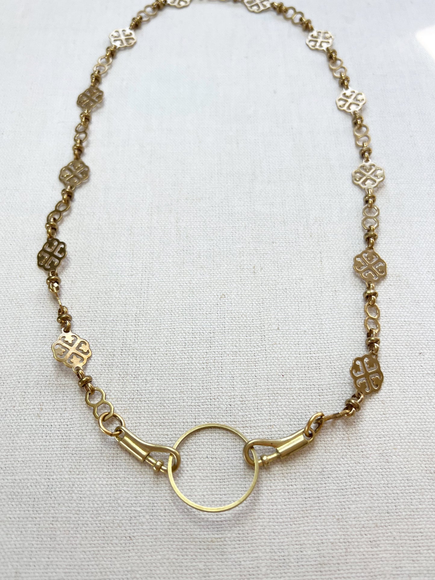 Gold necklace with a circular clasp on a white background