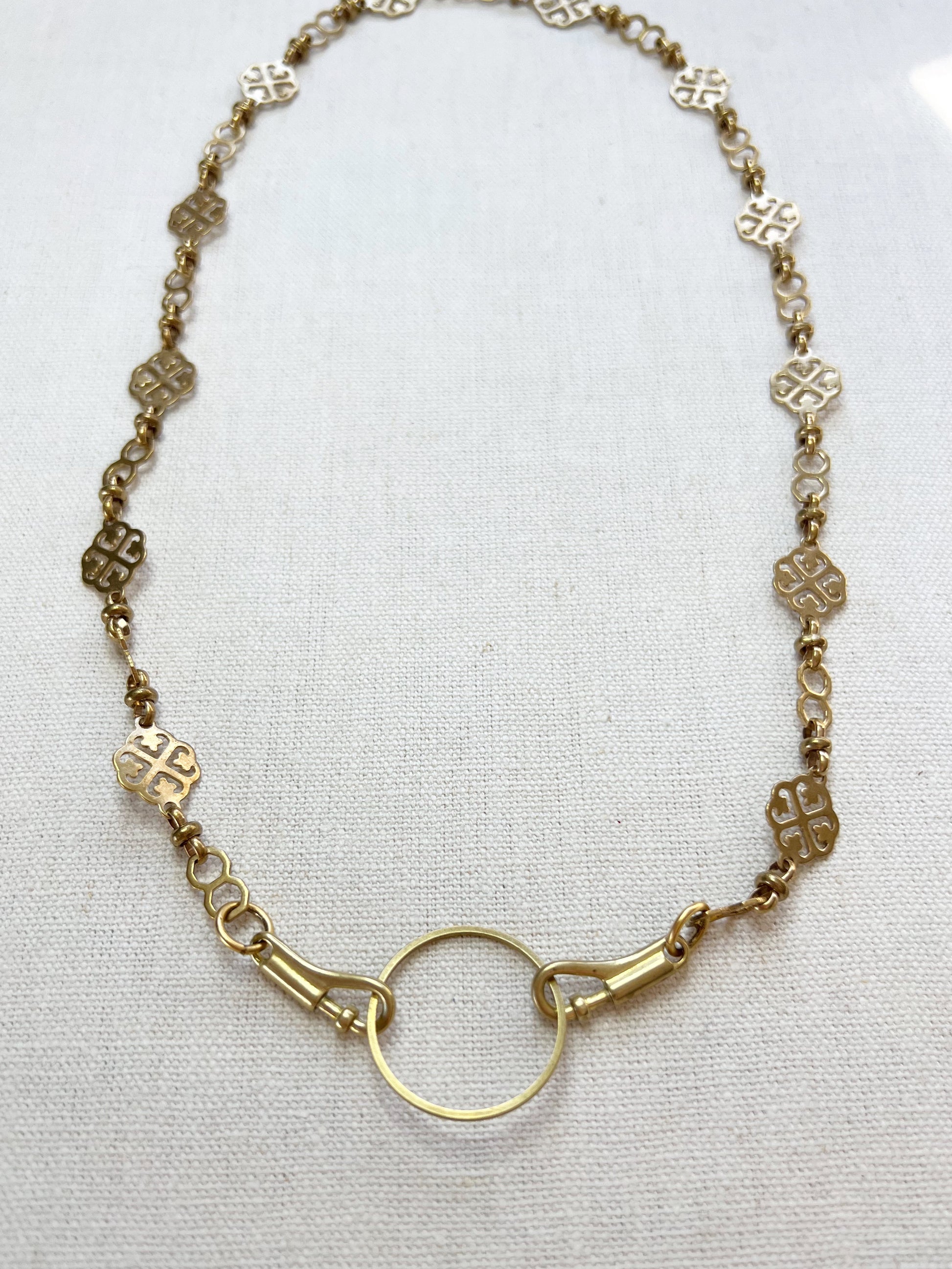 Gold necklace with a circular clasp on a white background