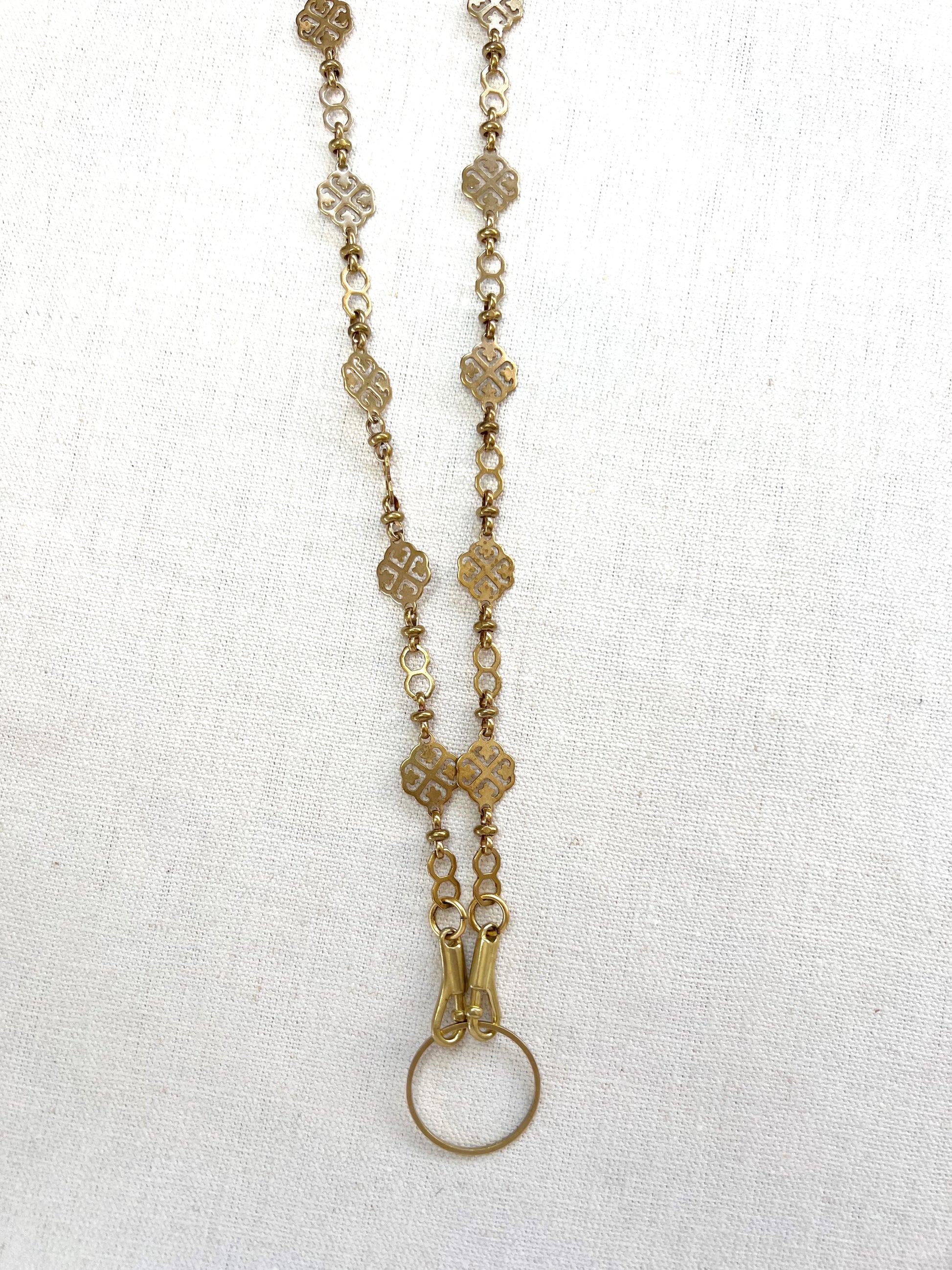 Gold chain necklace with floral designs on a white fabric background