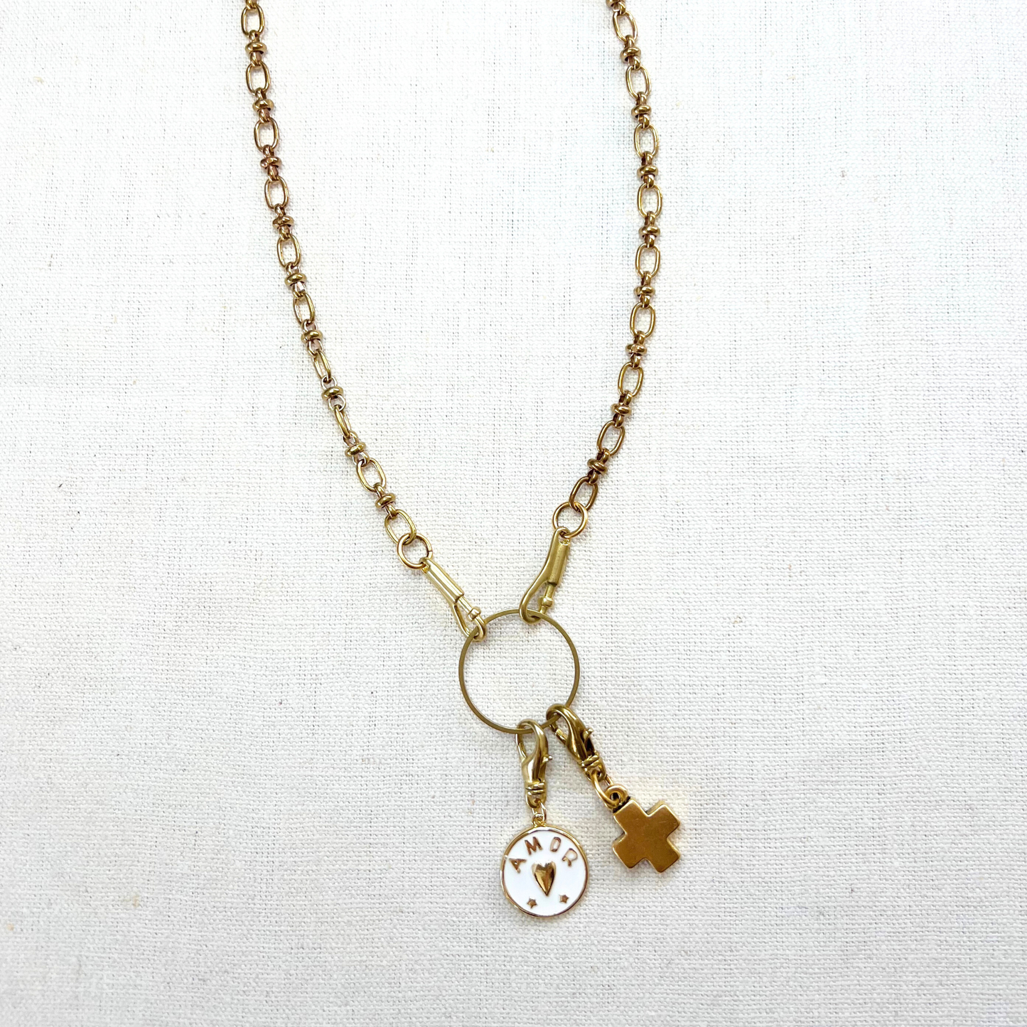 Gold necklace with charms on a white fabric background