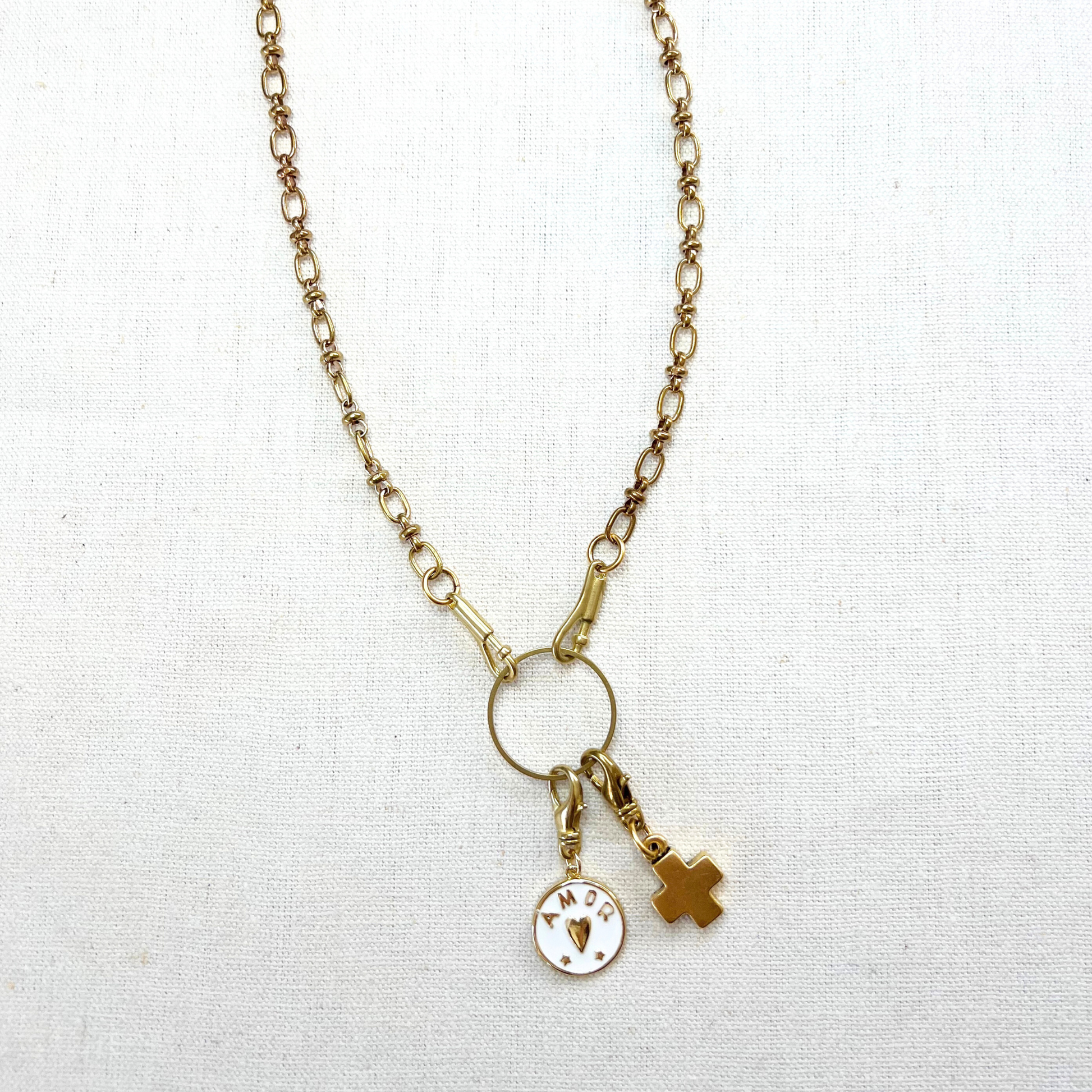 Gold necklace with charms on a white fabric background