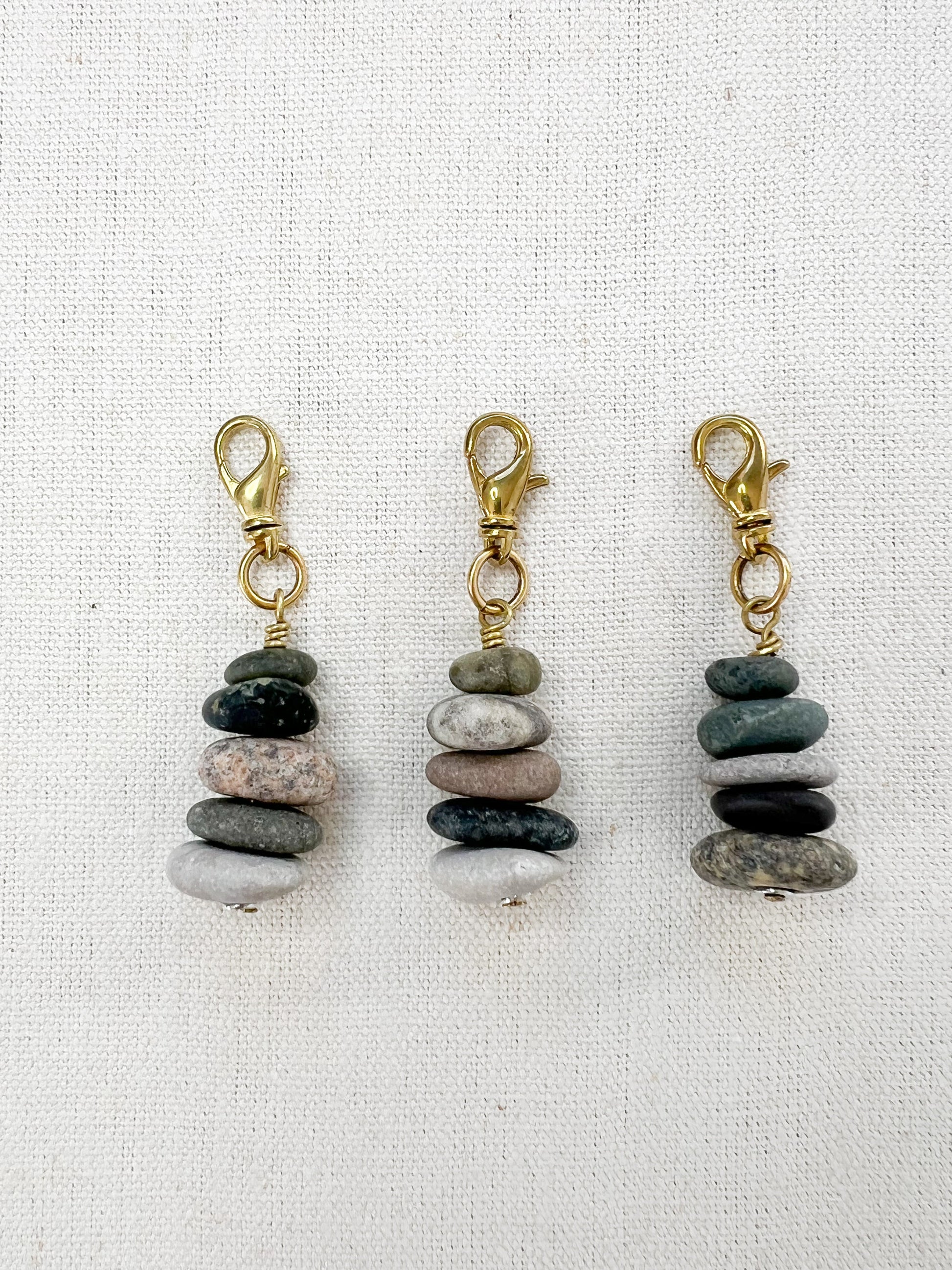 three stacked stone cair charms on white fabric background