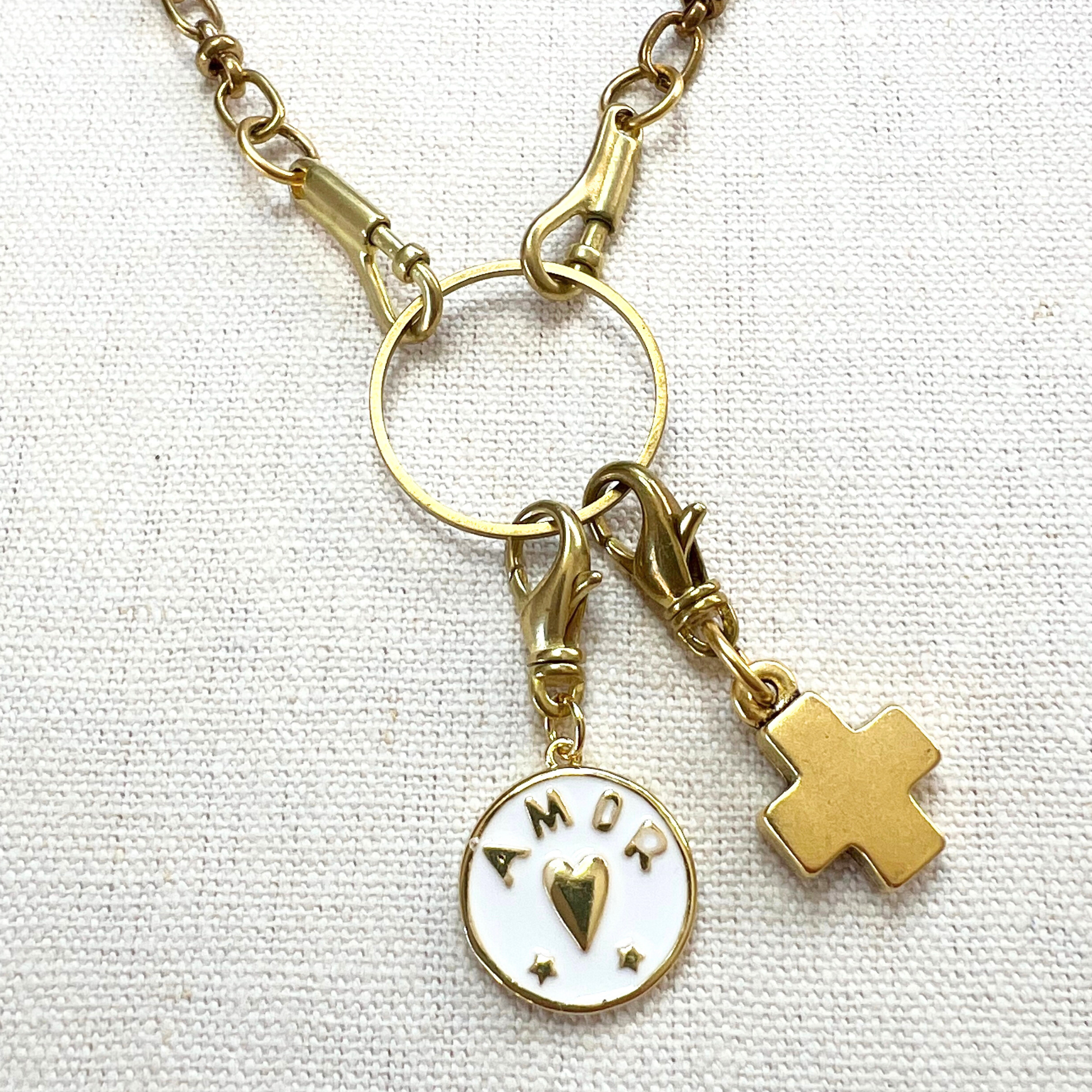 Gold necklace with charms on a textured white background