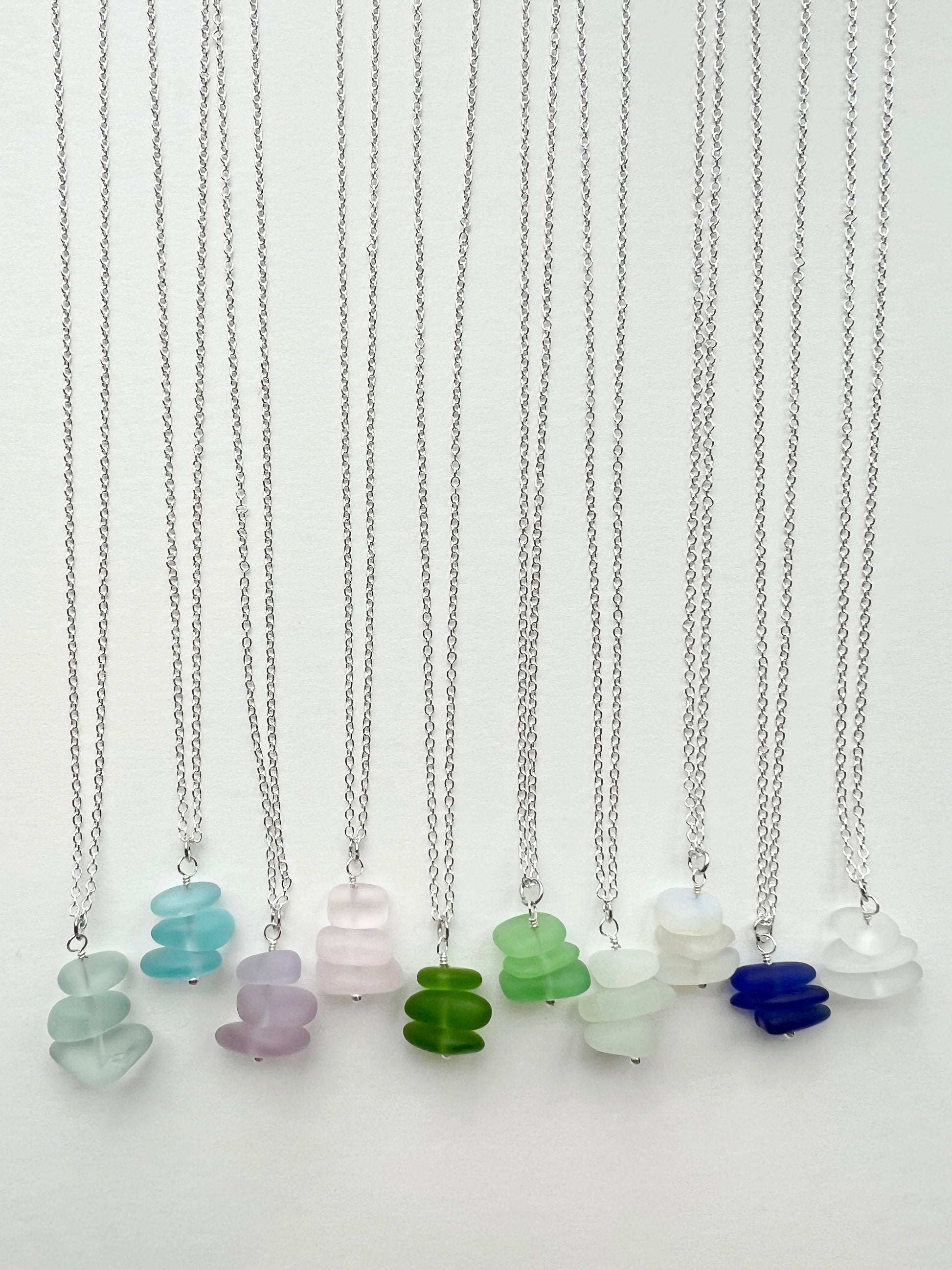 Beach glass necklaces with colorful glass pendants on a white background