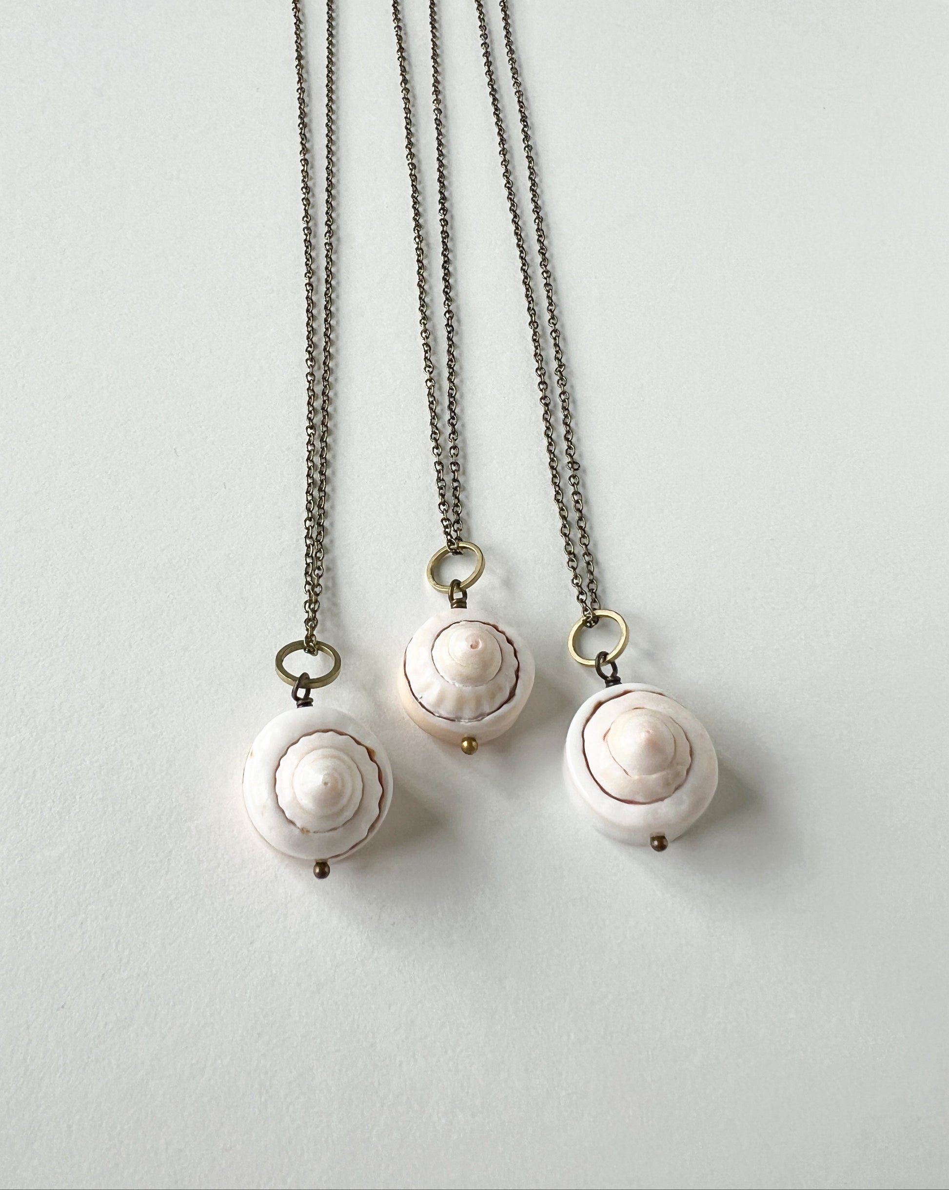 Three round shell necklaces on a light gray background