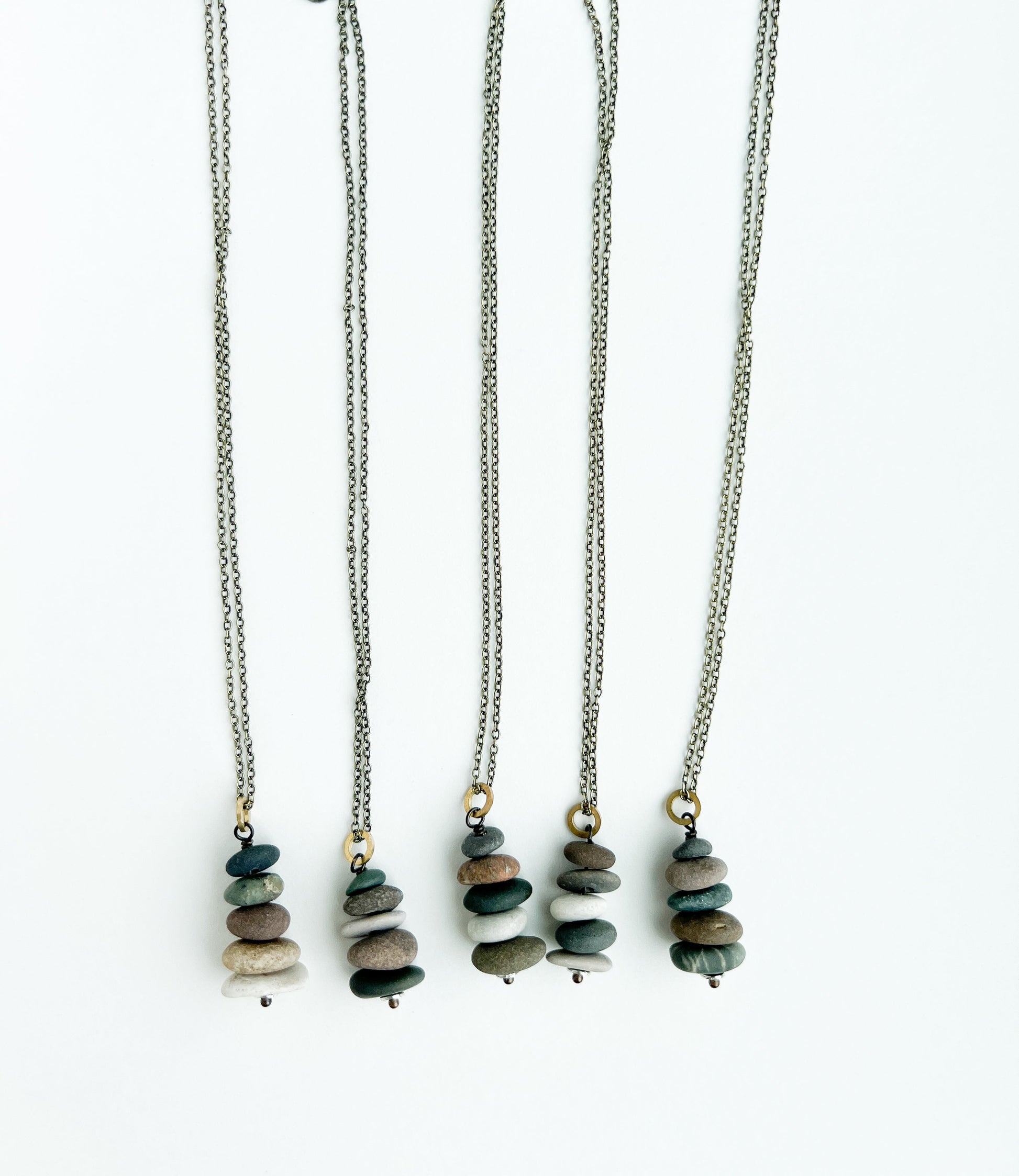 Five necklaces with stone pendants on a white background