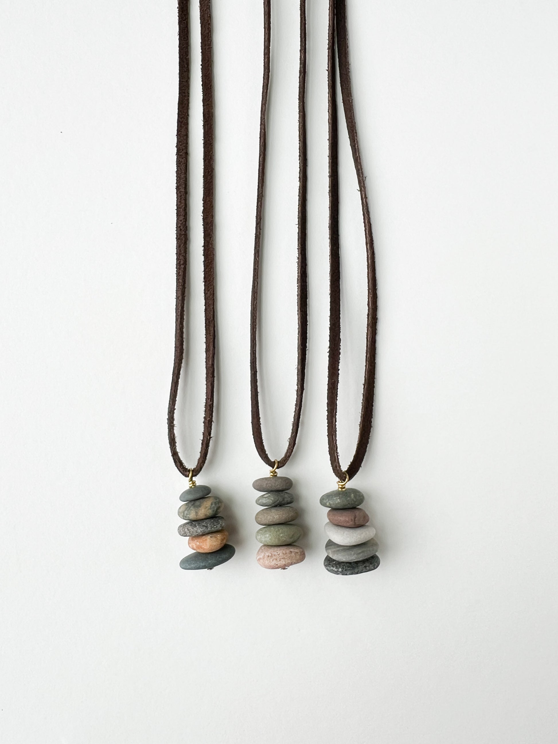 Three necklaces with stone pendants on a white background