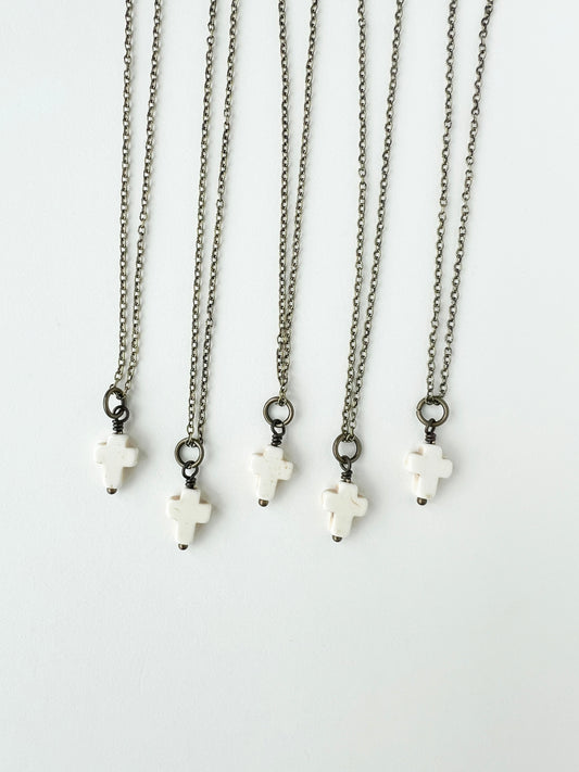 Set of five necklaces with white cross pendants on a white background