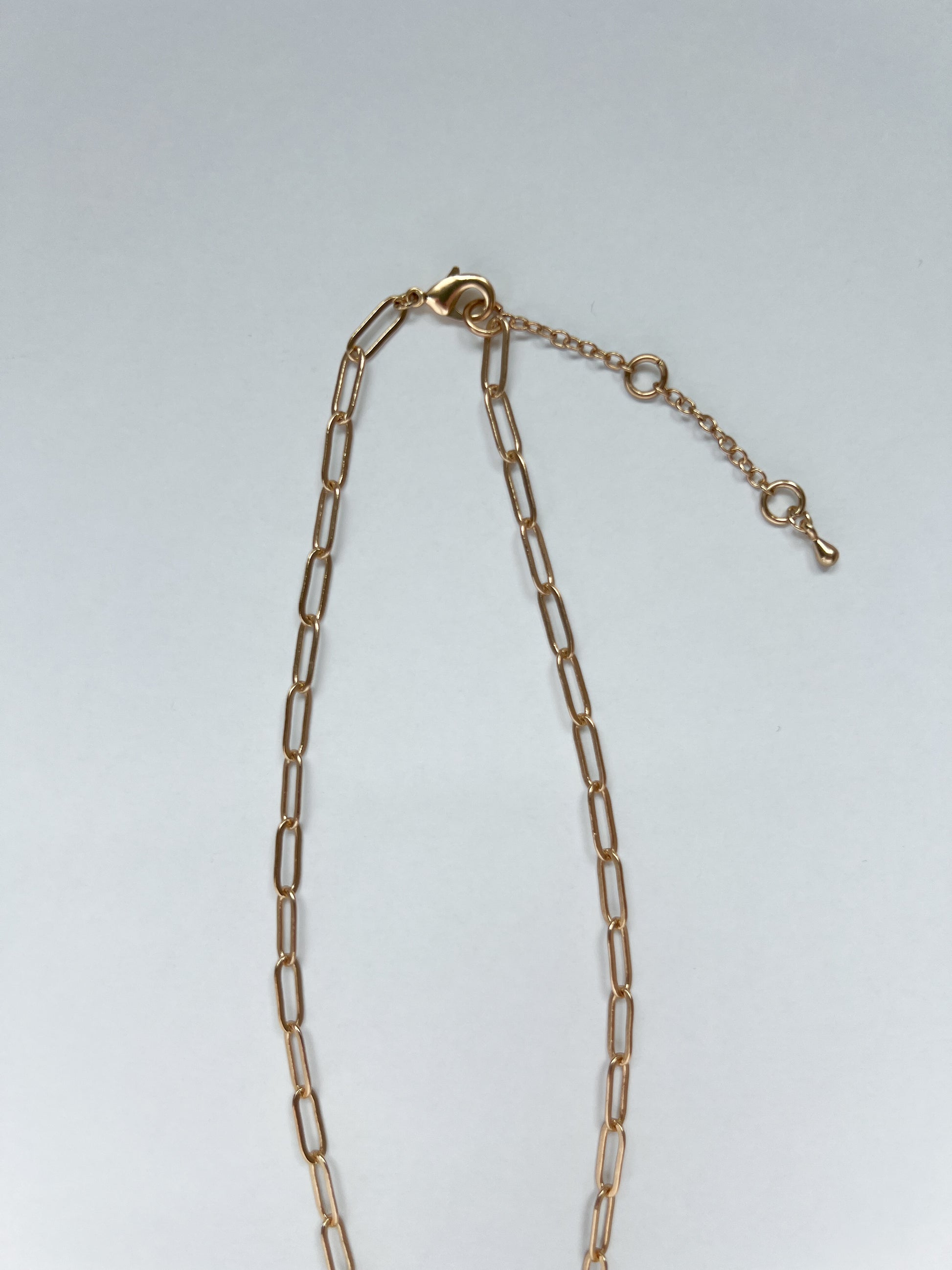 Brushed gold paperclip chain necklace on a white background