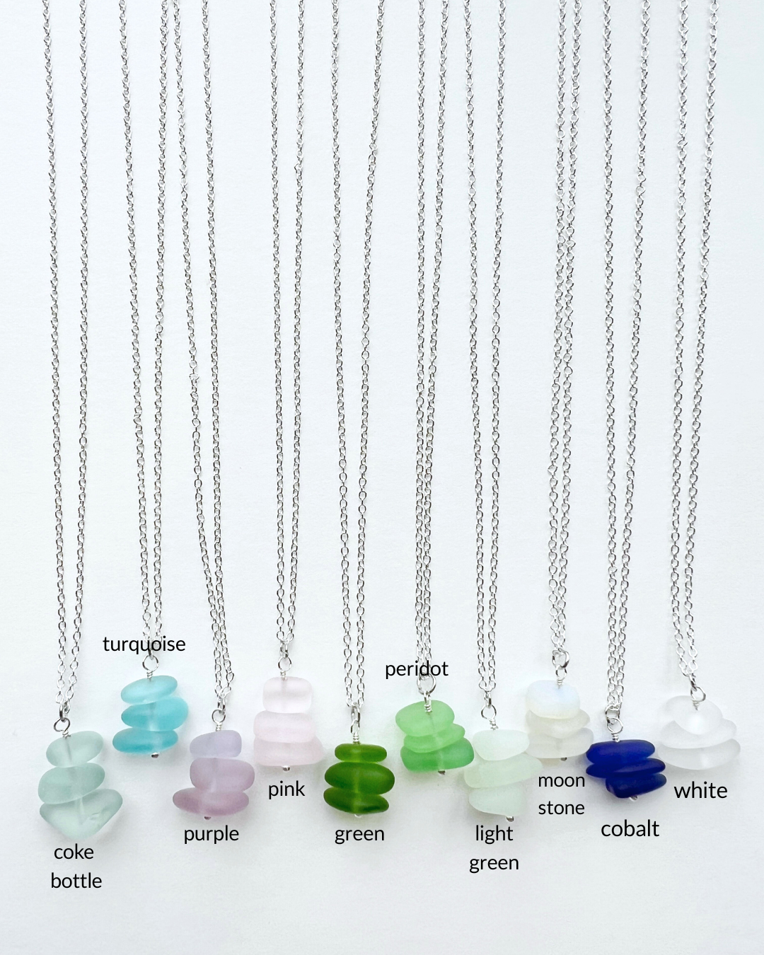 Beach glass necklaces with colored sea glass on a white background