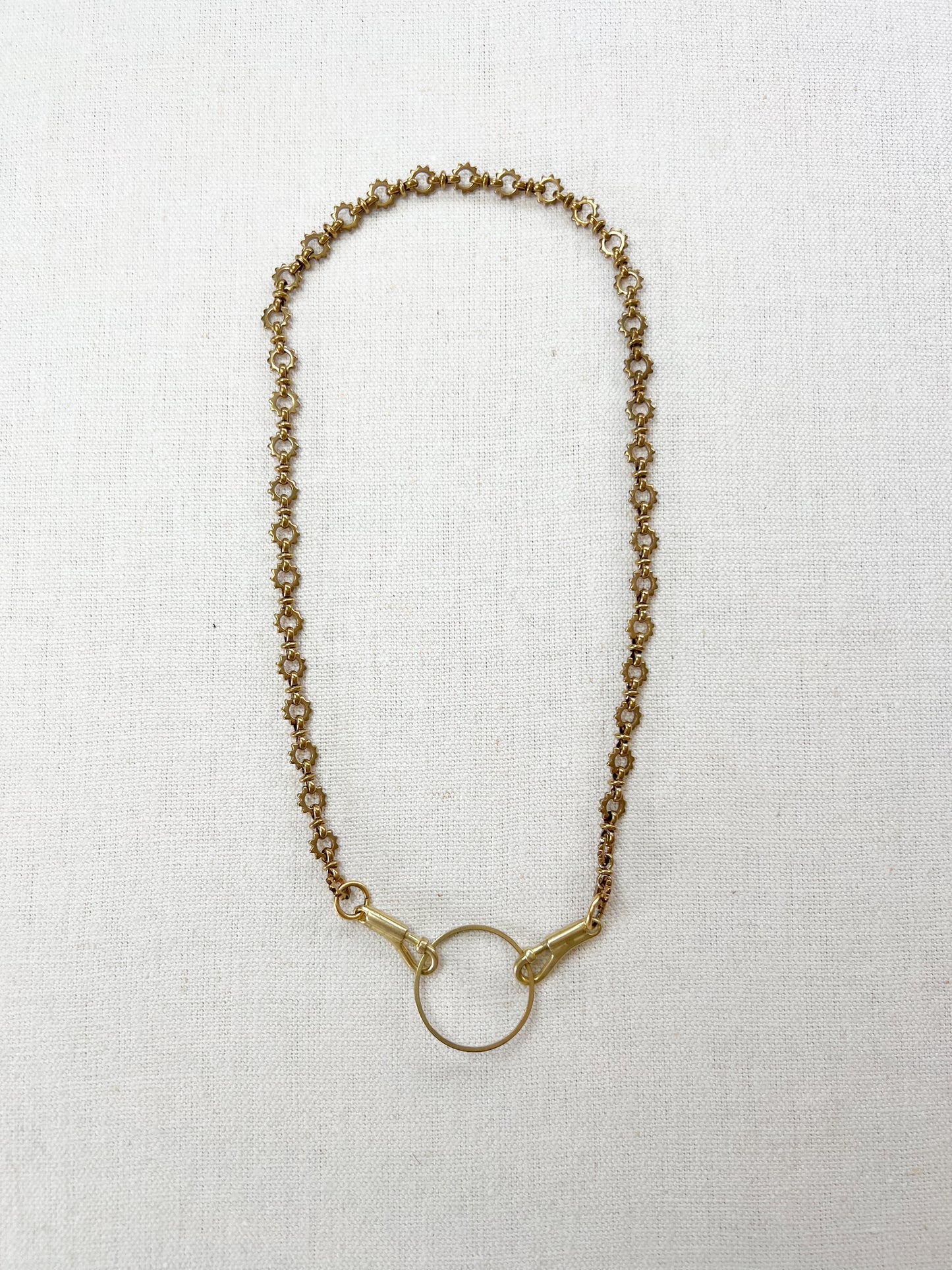 Gold chain charm necklace on a white fabric background