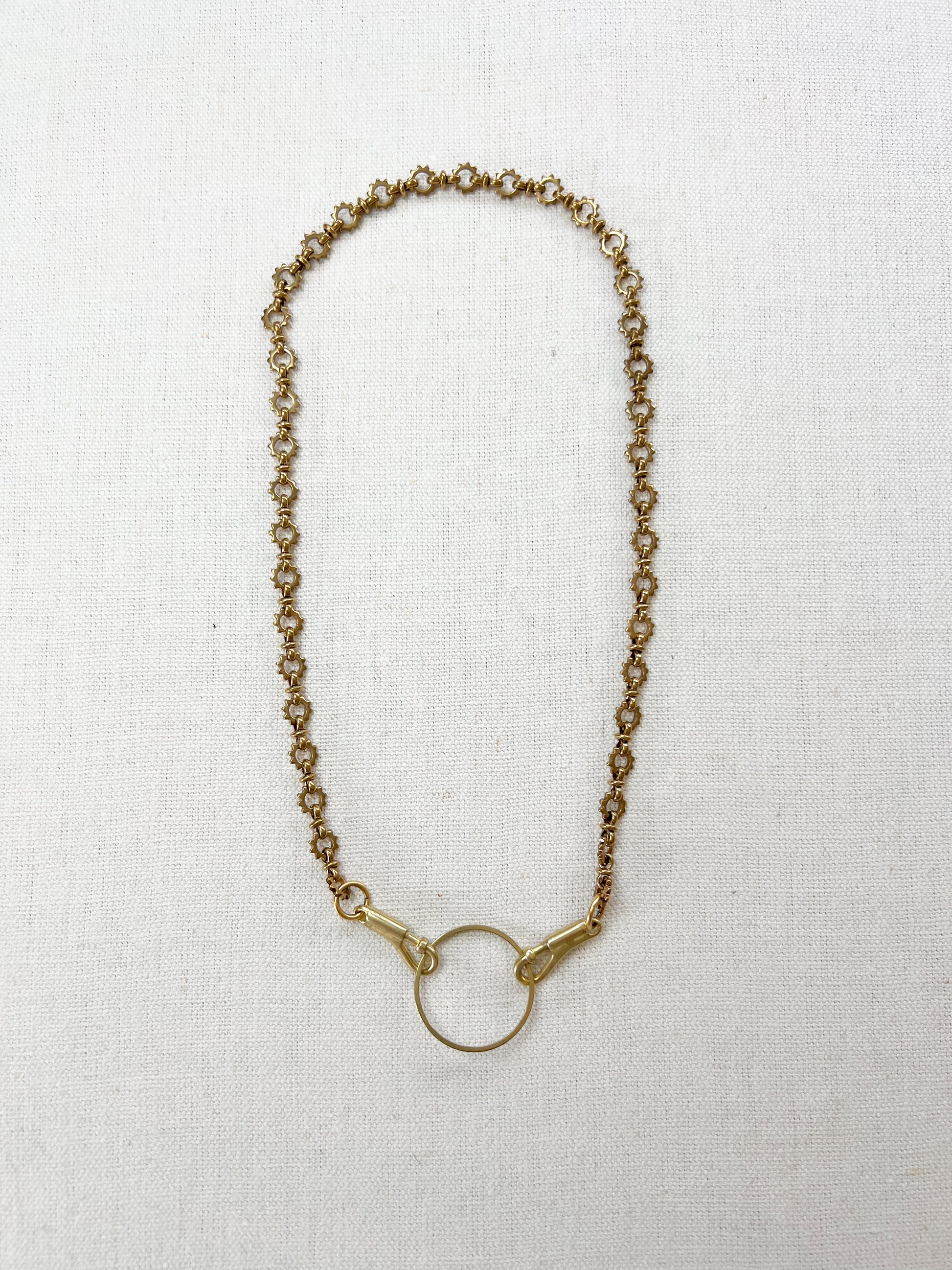 Gold chain charm necklace on a white fabric background