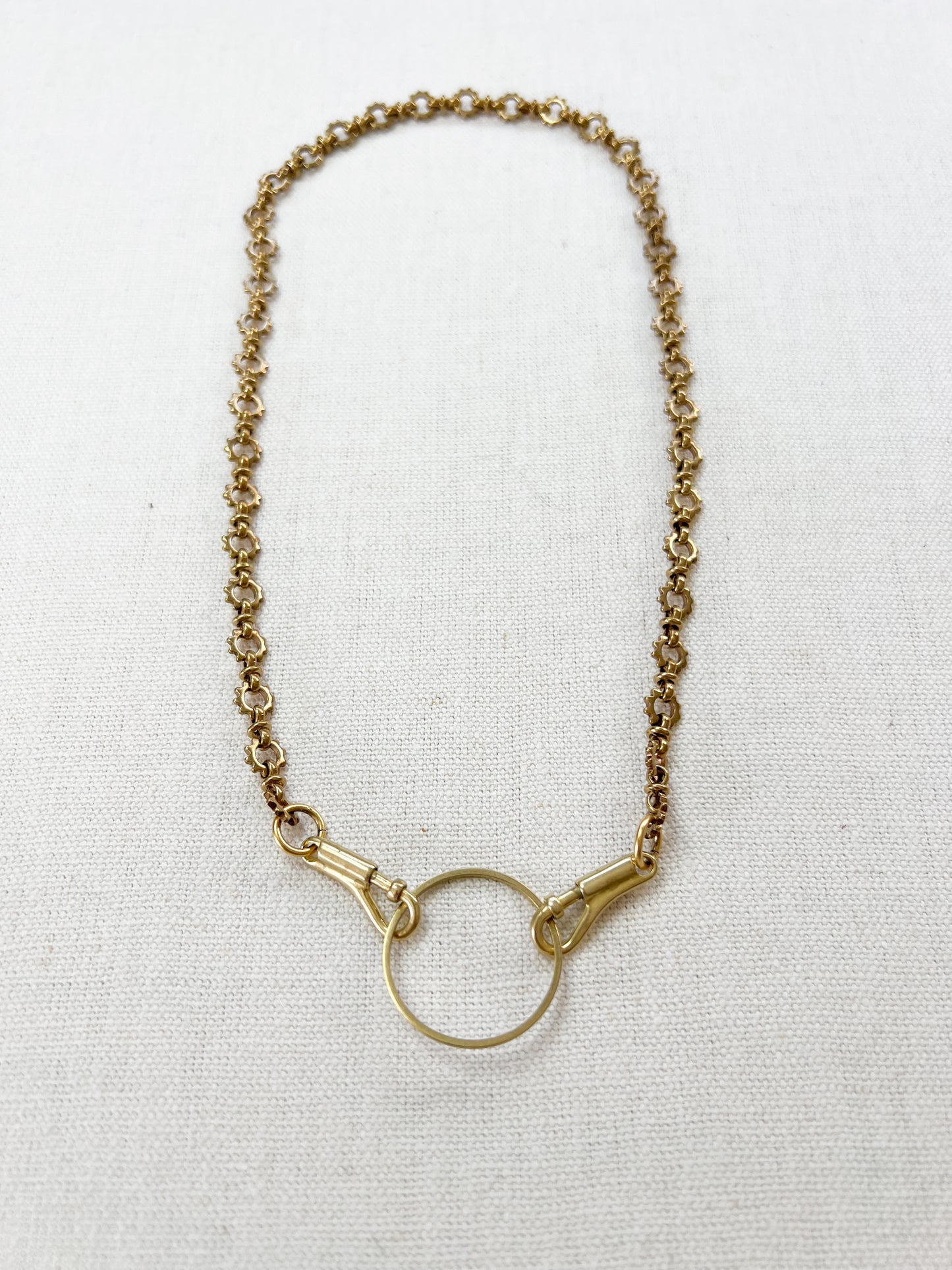 Gold necklace with a circular pendant on a white background