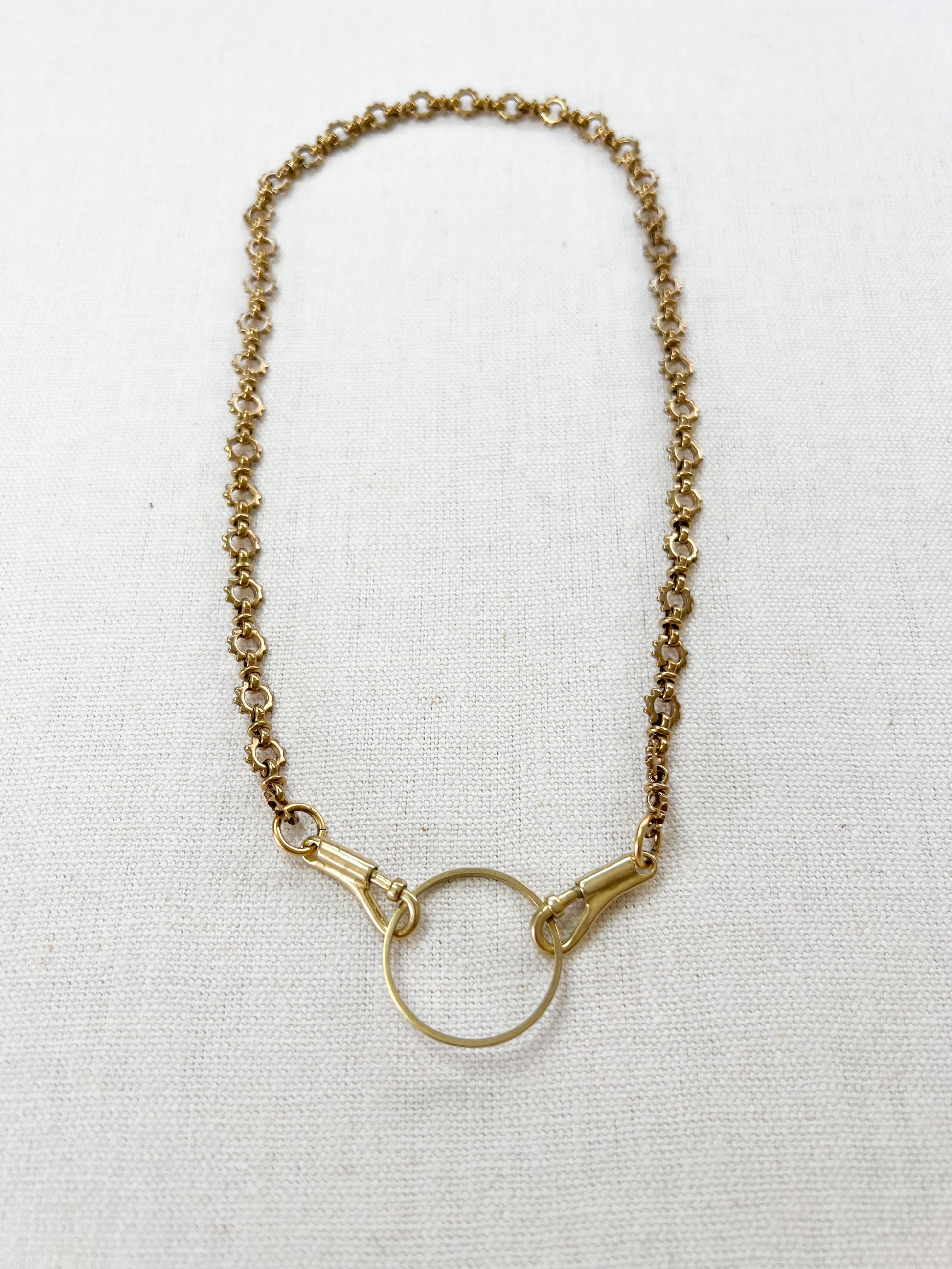 Gold necklace with a circular pendant on a white background